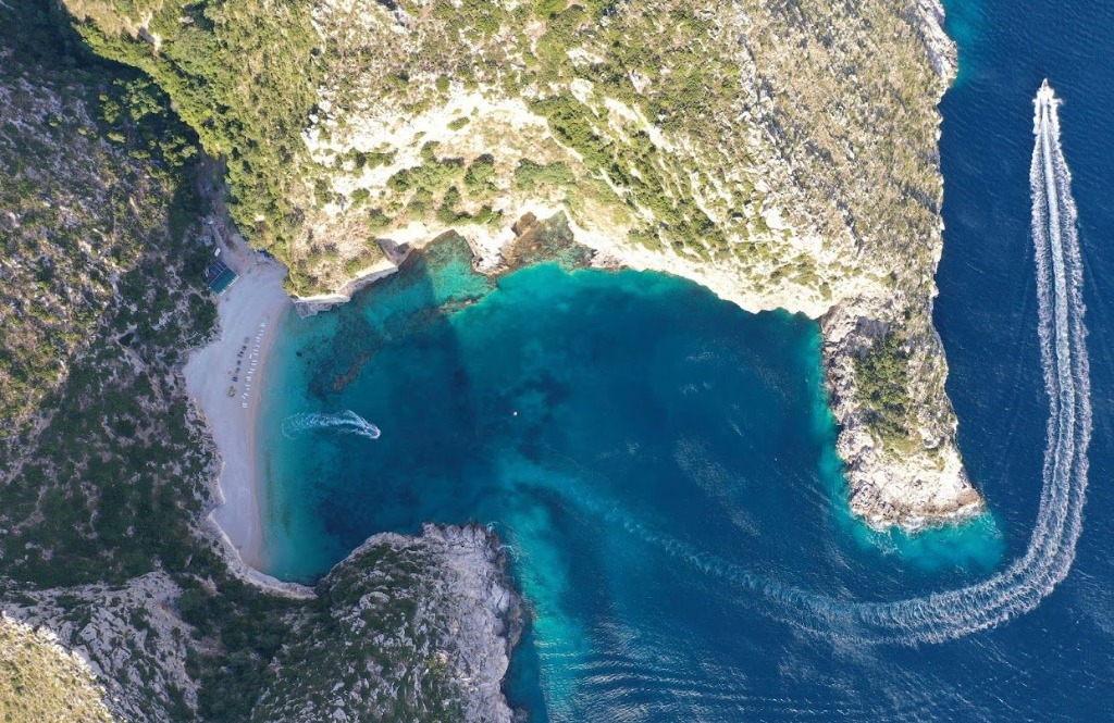 Speedboat anchored in the shallow turquoise waters of Gramma Bay, Albania